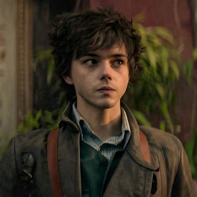 A young man with tousled brown hair and a dark green coat